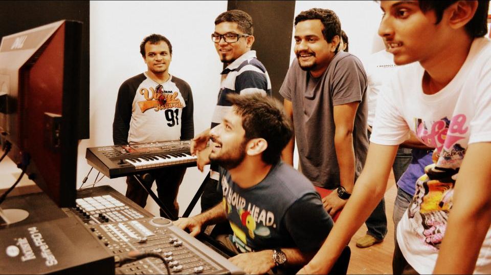 Students crowding around a mixer and synth at the Mega Masterclass